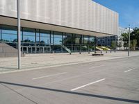 an empty parking lot in front of an office building with an open front door and glass windows