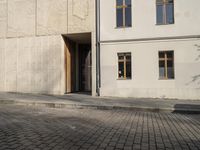 a person with a suitcase walking across an outside courtyard in front of a building,