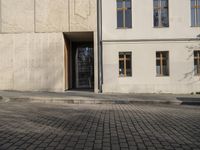 a person with a suitcase walking across an outside courtyard in front of a building,