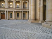 a courtyard with a building on the other side and a large white building with many windows