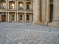 a courtyard with a building on the other side and a large white building with many windows