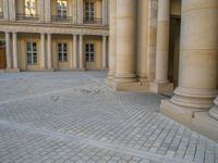 a courtyard with a building on the other side and a large white building with many windows