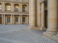 a courtyard with a building on the other side and a large white building with many windows