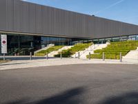 an open air parking space at the top of a hill with stairs, railings and grass and steps