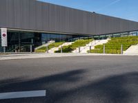 an open air parking space at the top of a hill with stairs, railings and grass and steps