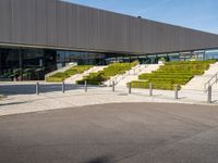 an open air parking space at the top of a hill with stairs, railings and grass and steps