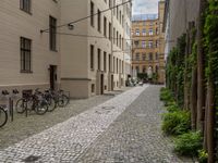 an empty brick road between buildings with bicycles parked on it's sides between the blocks