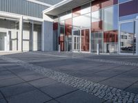 an empty sidewalk with large glass doors and no people walking down it next to a building