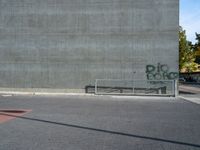 a view of a bench in front of a wall, with graffiti on it, near a park bench and fence