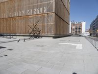 there is a building that has wood on the side of it and a bench with a shadow on the ground