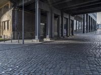 the sidewalk under an elevated bridge with columns and street lights, as well as street lights