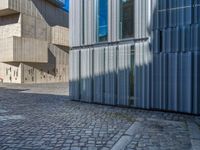 cobblestone driveway surrounded by modern buildings on sunny day with sun reflecting onto the windows