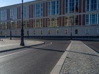 a street light next to an empty road in front of a building with a traffic light on top of it