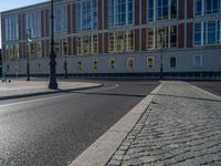 a street light next to an empty road in front of a building with a traffic light on top of it