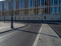 a street light next to an empty road in front of a building with a traffic light on top of it