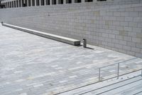 a concrete bench and railing outside an art gallery, looking down the stairs into a large brick courtyard