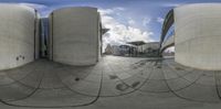 a sphere shaped object sits in front of a building with an artistic background of clouds