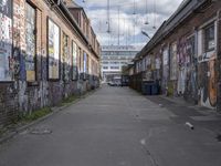 graffiti adorns the walls of an industrial area in an alleyway along a busy street