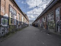 graffiti adorns the walls of an industrial area in an alleyway along a busy street