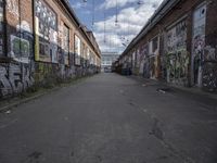 graffiti adorns the walls of an industrial area in an alleyway along a busy street