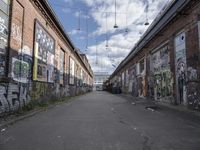 graffiti adorns the walls of an industrial area in an alleyway along a busy street