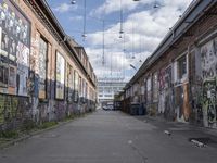 graffiti adorns the walls of an industrial area in an alleyway along a busy street