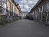 graffiti adorns the walls of an industrial area in an alleyway along a busy street