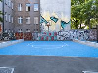 an outdoor basketball court surrounded by a bunch of other graffiti painted buildings in the background