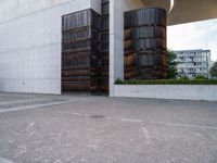 two brown barrels are in the parking lot by a building by itself outside on a sunny day