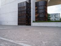 two brown barrels are in the parking lot by a building by itself outside on a sunny day