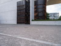 two brown barrels are in the parking lot by a building by itself outside on a sunny day