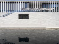 a reflection of another building on water in front of it and a black fire hydrant near the window