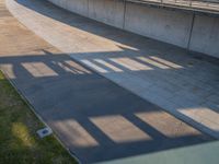 a skateboarder riding on a cement ramp next to a city street under a bridge