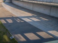 a skateboarder riding on a cement ramp next to a city street under a bridge