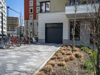 several bicycles are lined up outside a city apartment building and parking lot with a large garage