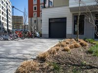 several bicycles are lined up outside a city apartment building and parking lot with a large garage