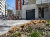 several bicycles are lined up outside a city apartment building and parking lot with a large garage