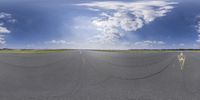 this is a panorama of the runway from above with no vehicles in it and clouds are forming