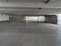 an empty parking garage with one door open for cars to pass by in it that appears to be the middle floor