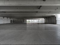 an empty parking garage with one door open for cars to pass by in it that appears to be the middle floor