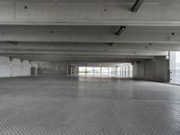 an empty parking garage with one door open for cars to pass by in it that appears to be the middle floor