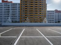 a large apartment building with some white lines in a parking lot with concrete blocks on either side