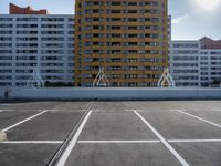 a large apartment building with some white lines in a parking lot with concrete blocks on either side