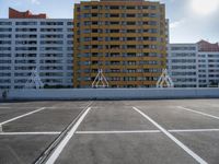 a large apartment building with some white lines in a parking lot with concrete blocks on either side