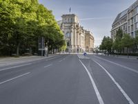 empty street with trees and a building in the back ground, with white marking on it