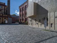 cobblestone driveway surrounded by modern buildings on sunny day with sun reflecting onto the windows