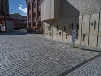 cobblestone driveway surrounded by modern buildings on sunny day with sun reflecting onto the windows