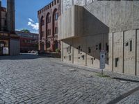 cobblestone driveway surrounded by modern buildings on sunny day with sun reflecting onto the windows