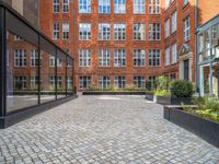 an empty parking lot with plants in the ground and on the side of the building, there is an enclosed area and windows