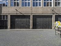 a bench sitting in front of a tall building with several windows in the background,